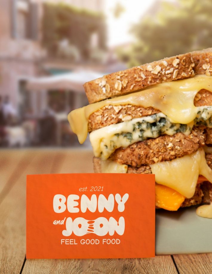 Carte de visite de Benny and Joon avec leur logo, accompagnée d'un de leurs délicieux sandwiches garnis.